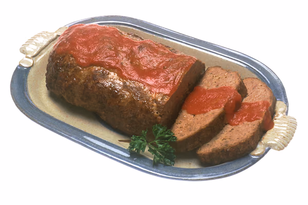 Bolo de carne assado com cobertura de molho de tomate, com fatias cortadas numa travessa