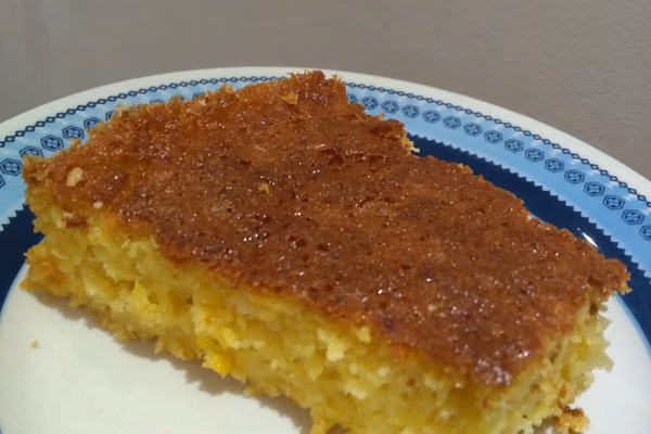 Bolo de milho dourado cortado em pedaços, mostrando o miolo úmido e amarelo