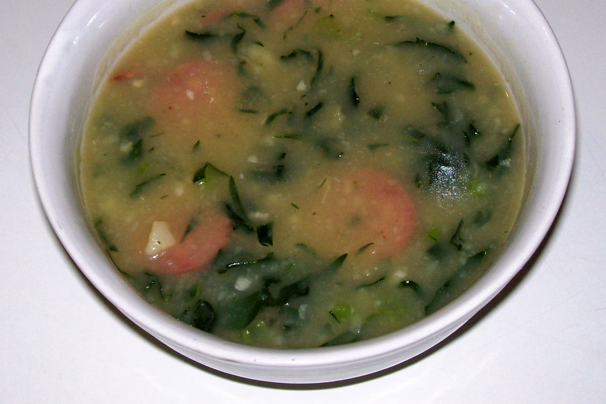 Tigela de caldo verde cremoso com rodelas de linguiça calabresa e fio de azeite por cima