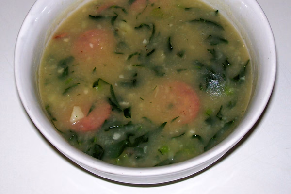 Tigela de caldo verde cremoso com rodelas de linguiça calabresa e fio de azeite por cima