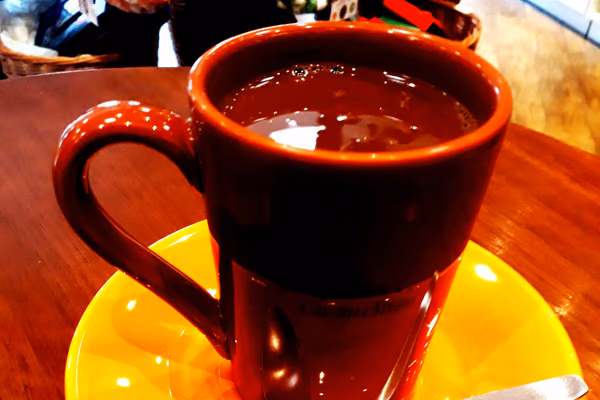 Caneca de cerâmica cheia de chocolate quente escuro e espesso, sobre pires amarelo