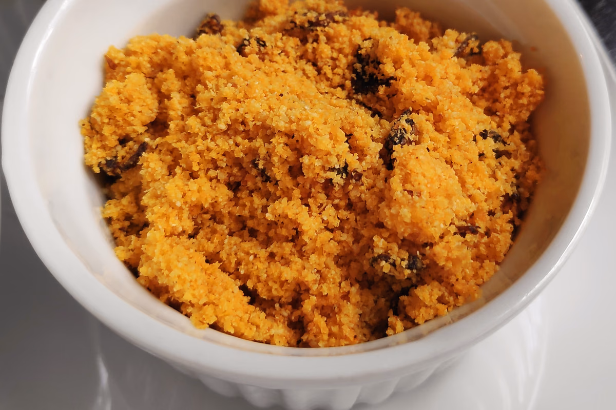 Tigela branca com farofa de cebola dourada e soltinha ao lado de arroz branco