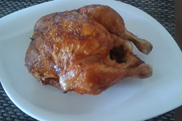 Frango assado inteiro e dourado servido em prato branco