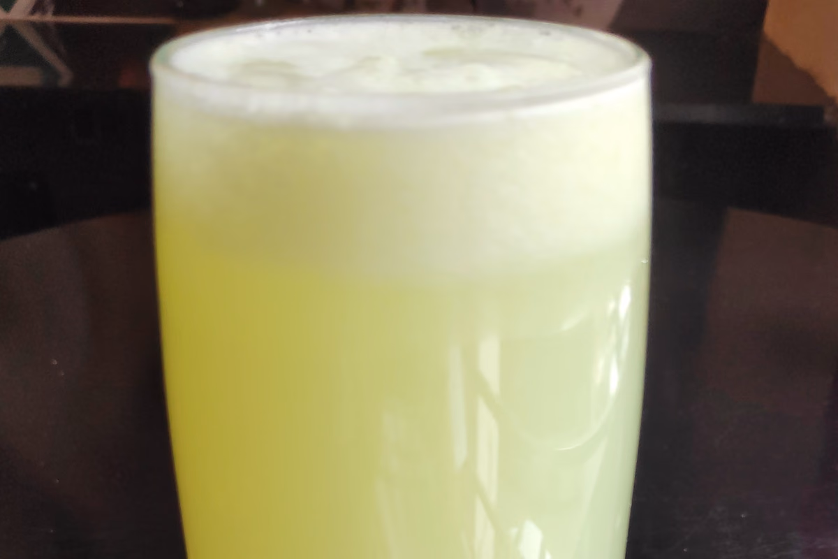 Copo alto com limonada suíça cremosa esverdeada e camada de espuma clara no topo