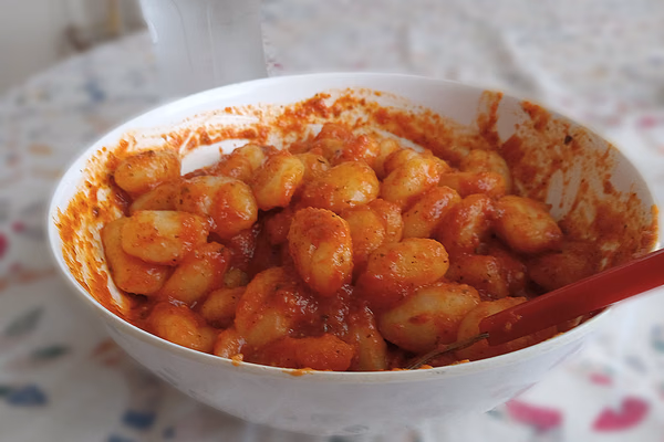 Prato de nhoque de batata coberto com molho vermelho de tomate e manjericão fresco