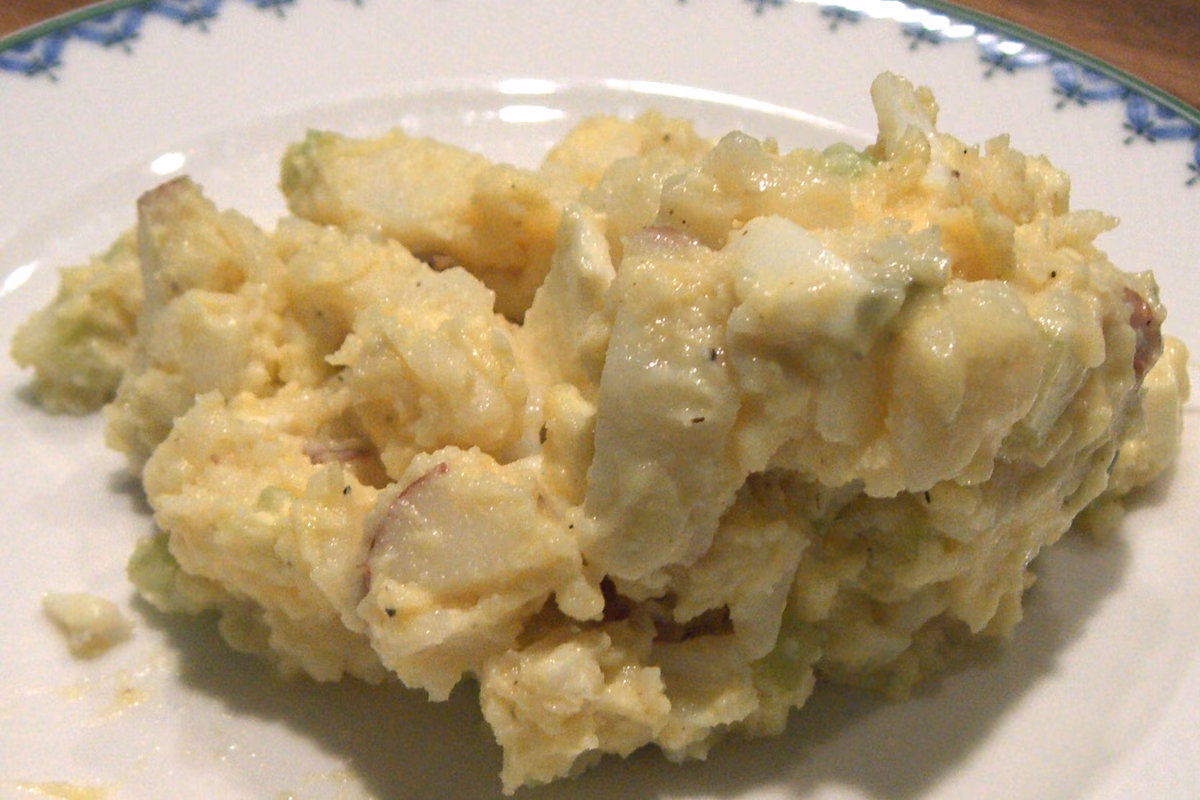 Tigela de salada de batata com maionese, pedaços de ovo cozido e salsinha picada